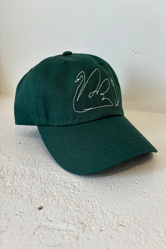 A green baseball cap with a white embroidered swan line drawing on the front.