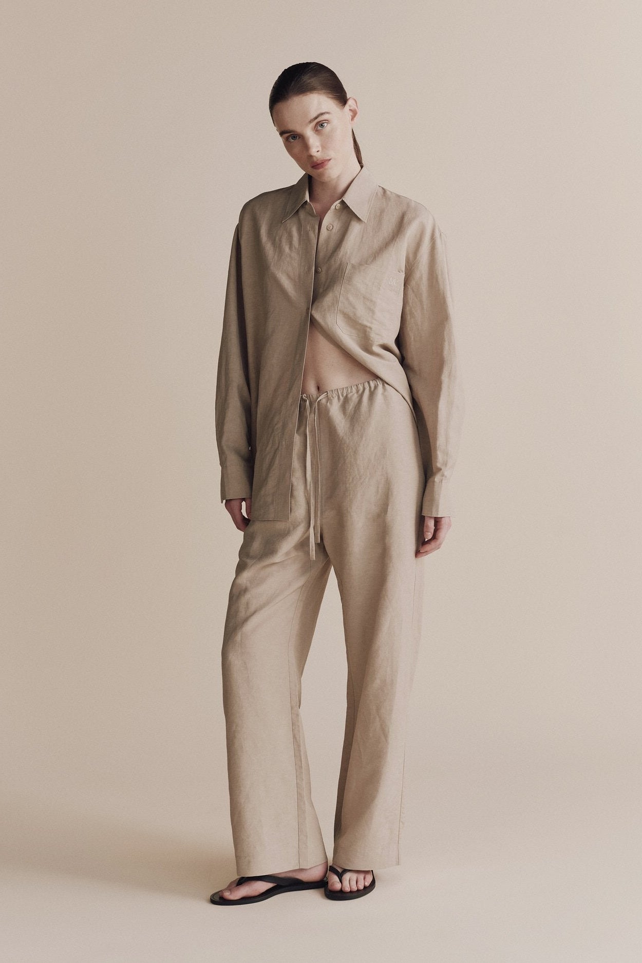 Person wearing a beige shirt and pants on a neutral background