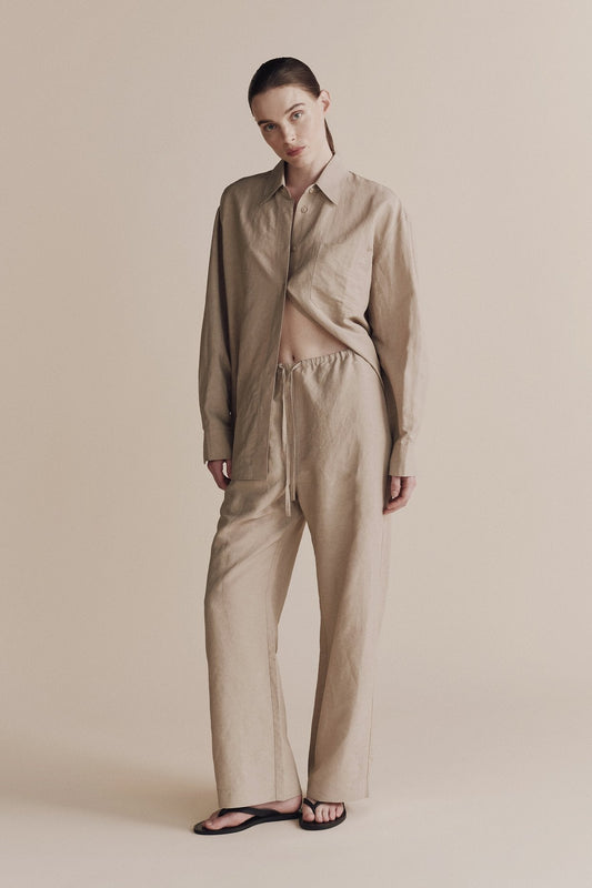 Person wearing a beige shirt and pants on a neutral background