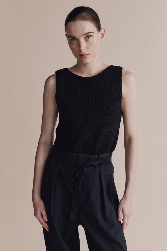 Person wearing a black sleeveless top and pants on a neutral background