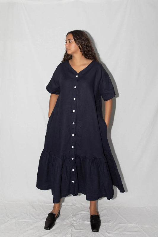 Woman wearing a navy blue dress with white buttons on a white background