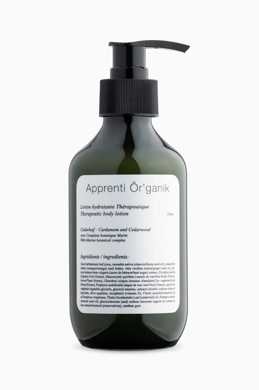A pump bottle of Apprenti Ér'ganik body lotion with labels detailing the product's ingredients and scents, primarily cedarleaf and cardamom.