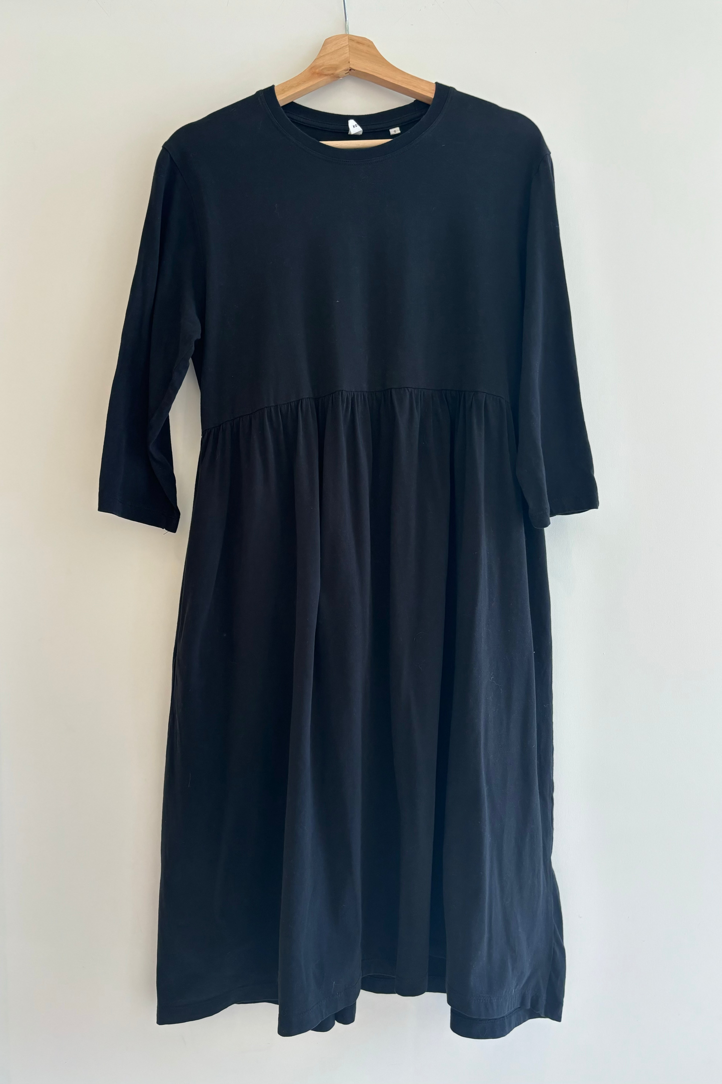 Navy blue dress on a hanger against a white background