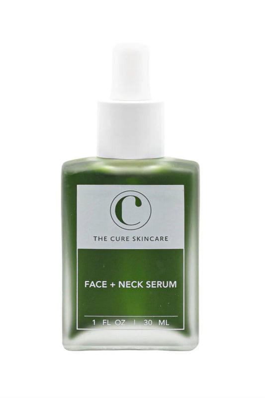A clear glass bottle with a white dropper containing a green-colored face and neck serum. The label has 'C' logo and text reading 'THE CURE SKINCARE FACE + NECK SERUM'.