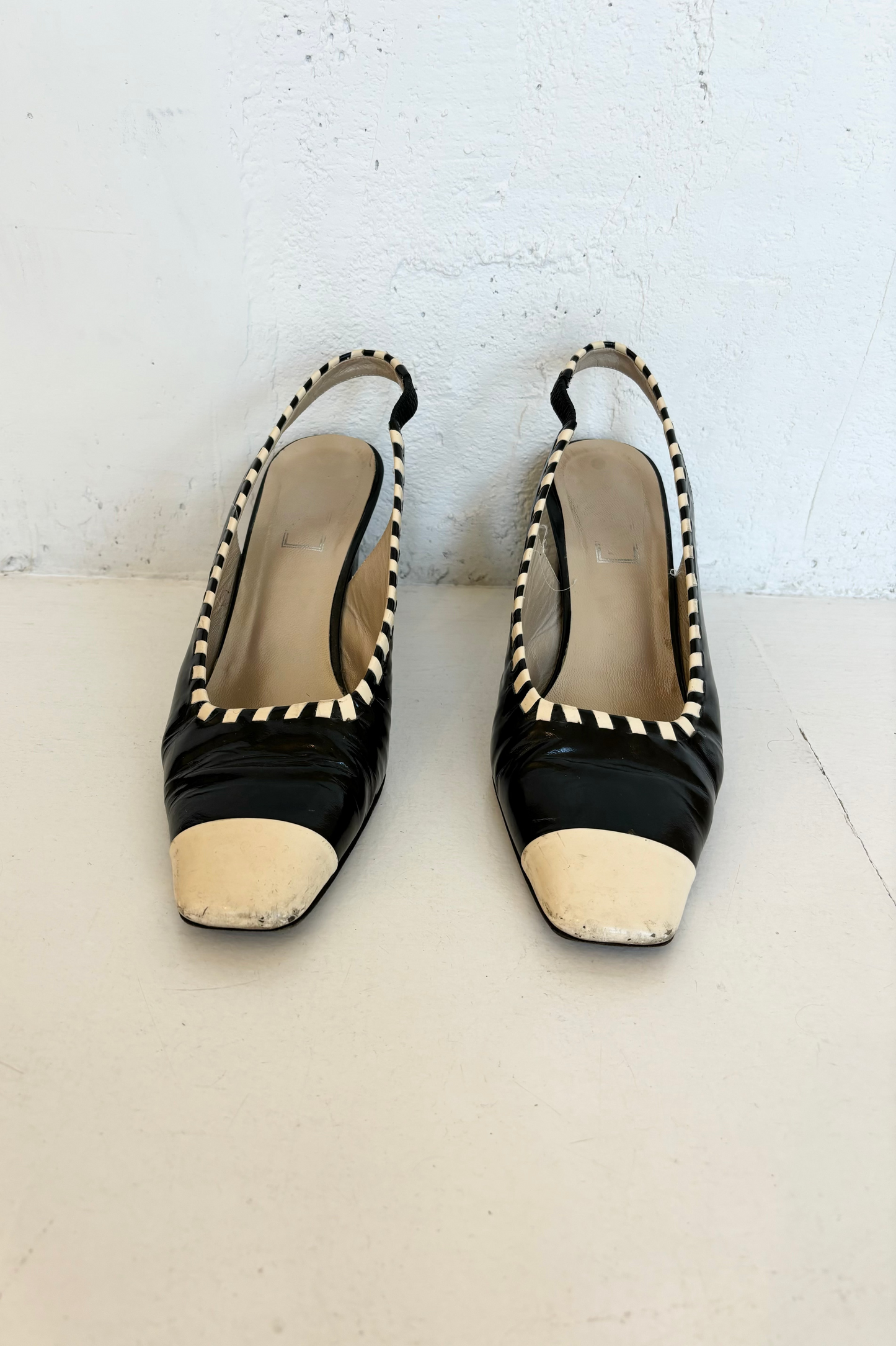 A pair of vintage black and white slingback shoes placed against a white background.