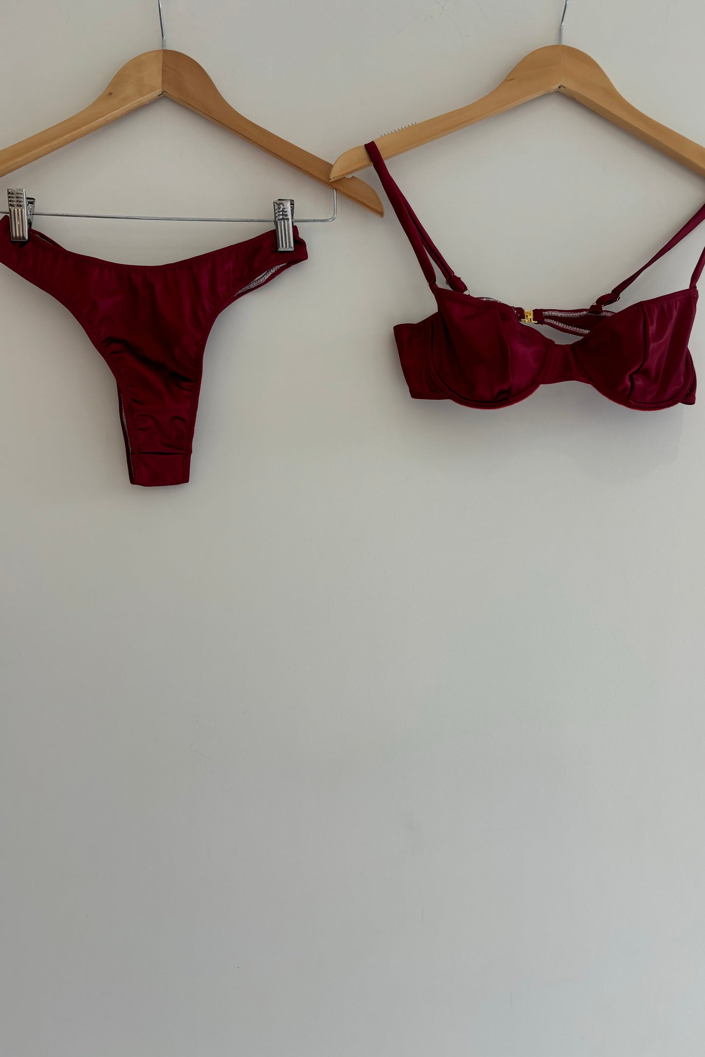 Burgundy bikini set on hangers against a white wall