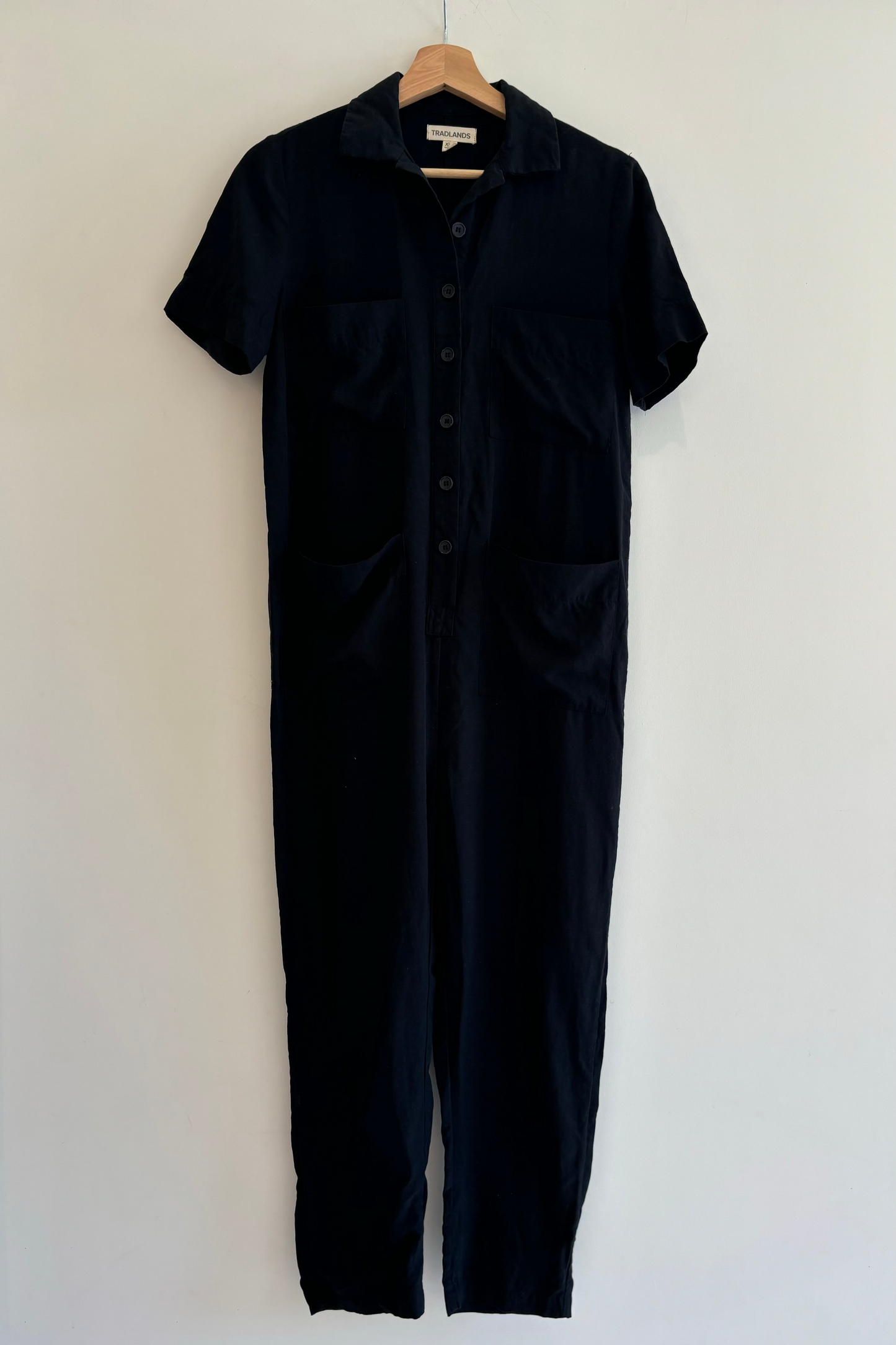 Black jumpsuit on a hanger against a white background