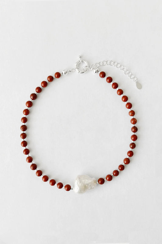 Necklace with red beads and a white pearl on a white background