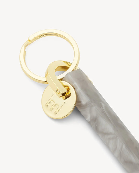 light grey marbled acetate keychain with gold hardware with M engraved on it