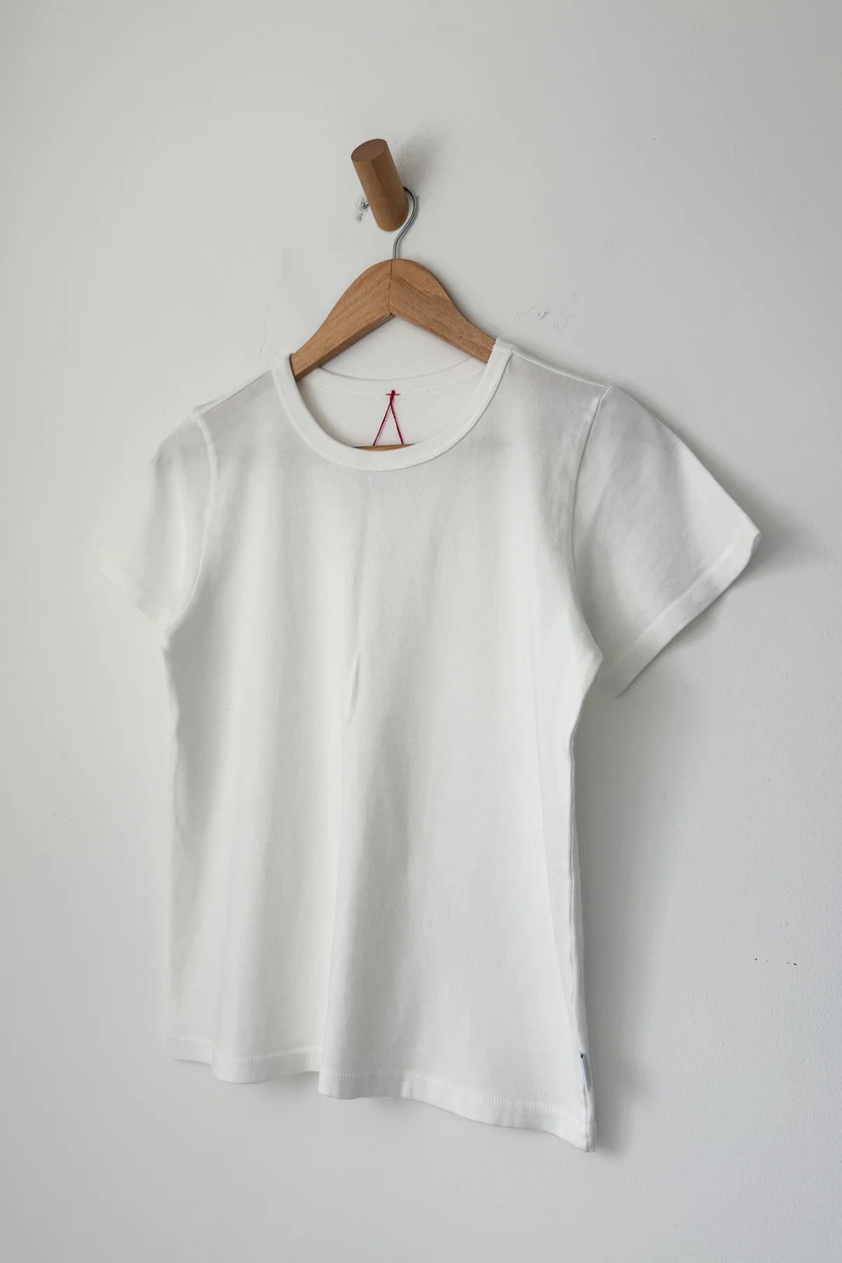 Le Bon Shoppe Go-To Tee in vintage white on a wooden hanger against a white wall, showing relaxed longer length silhouette, crew neck and short sleeves