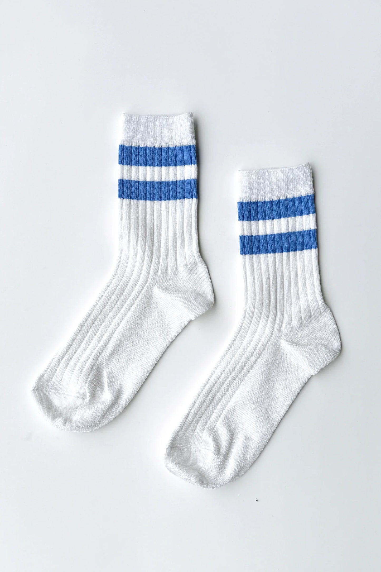 Pair of Le Bon Shoppe Her Varsity Socks in periwinkle laid flat on a white surface, showing white ribbed cotton-blend with periwinkle double stripe detail and quarter-crew length