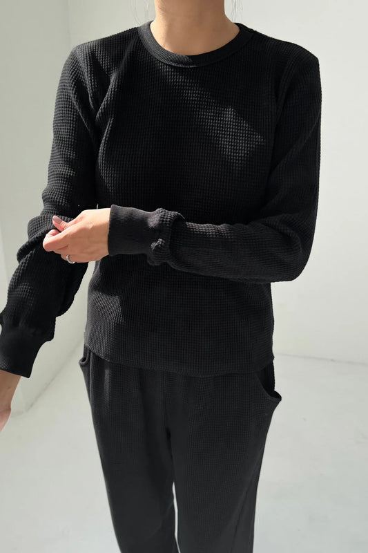 Close-up of Le Bon Shoppe Waffle Fundamental Tee in true black showing heavyweight waffle cotton texture and baby ribbed cuff detail, styled with matching Waffle Lo Pants