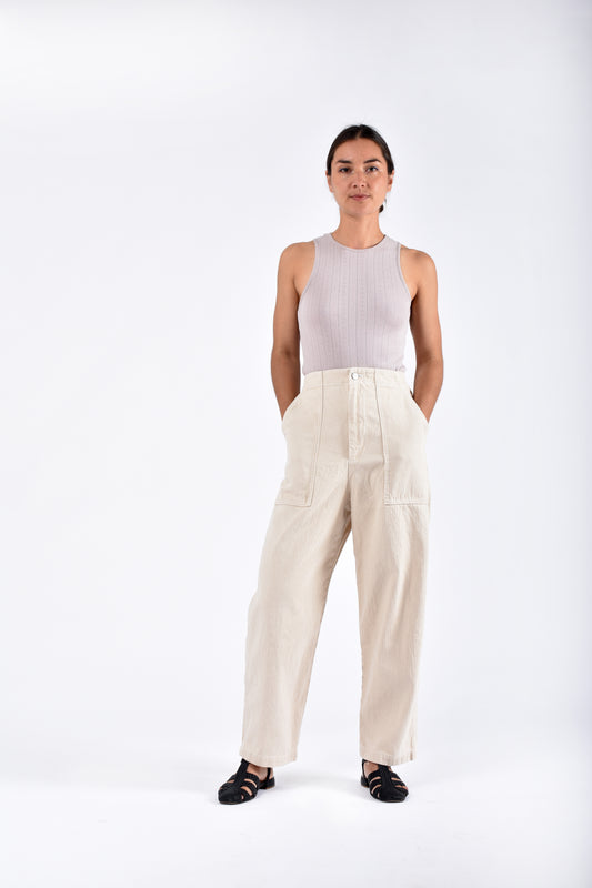 A model wearing a sleeveless top and Painter Pant in natural color, standing against a white background.
