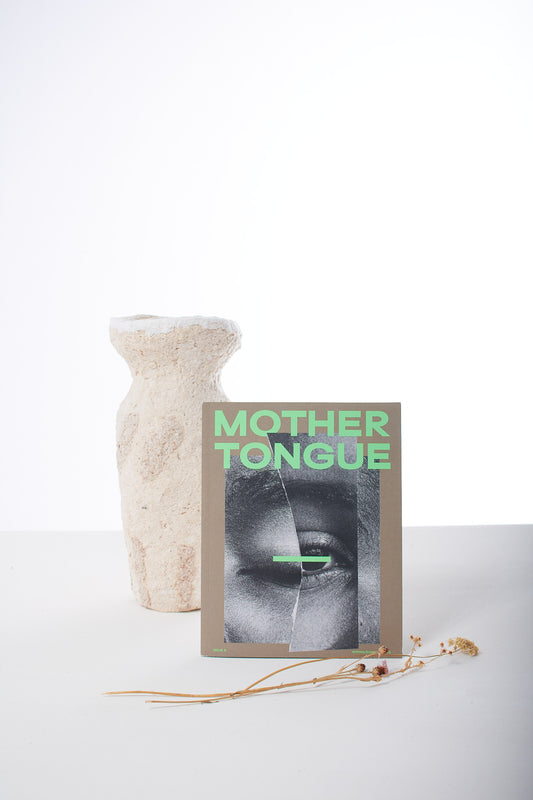 A magazine titled 'Mother Tongue' displayed on a table with a decorative vase in the background.