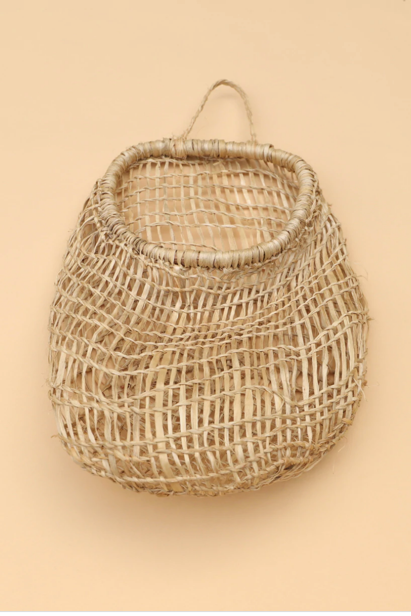 A beige, hand woven hanging basket with a braided handle and a wooden frame opening, displayed against a neutral background.