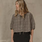 Woman wearing a plaid shirt against a beige wall