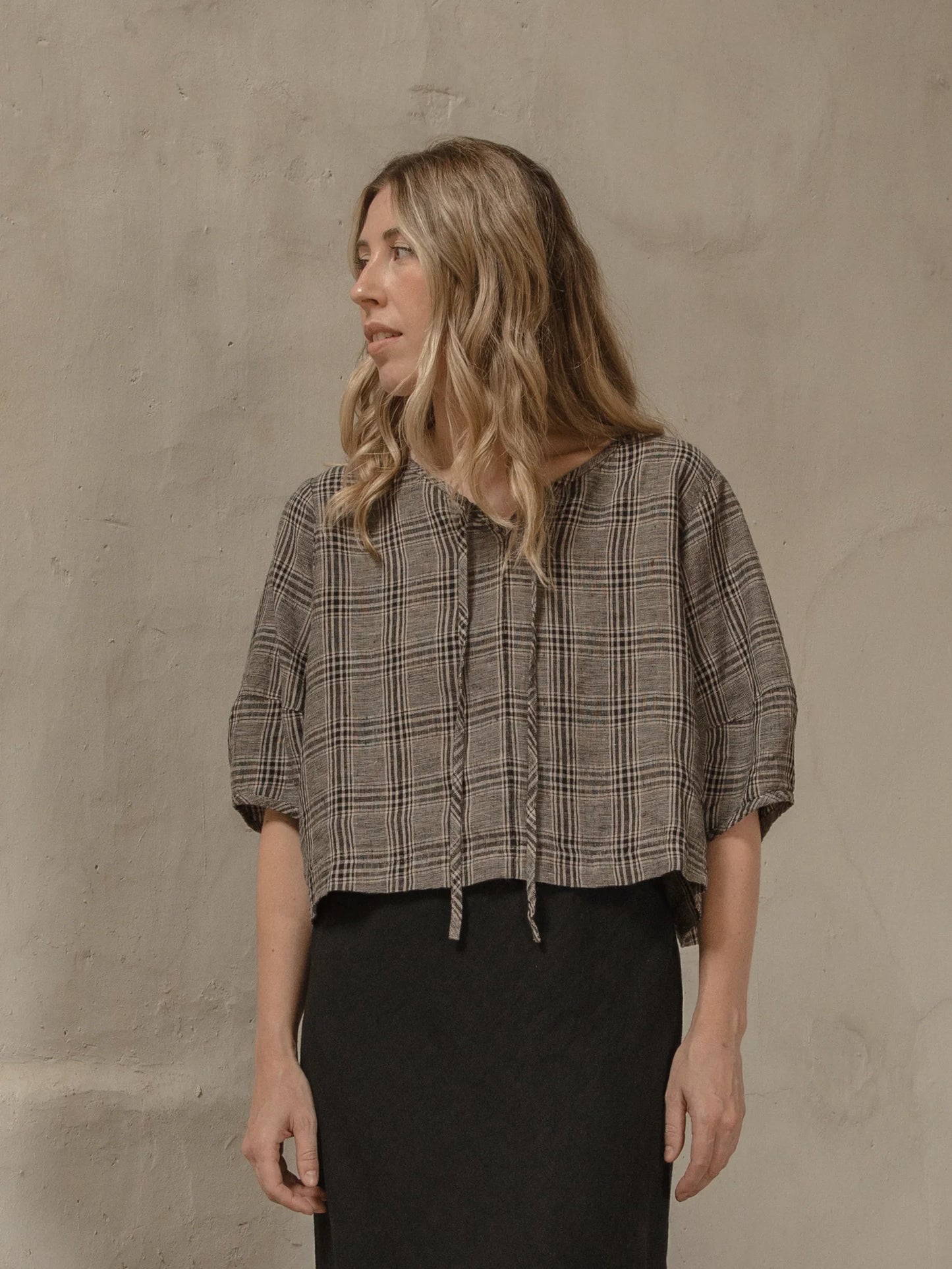 Woman wearing a plaid shirt against a beige wall