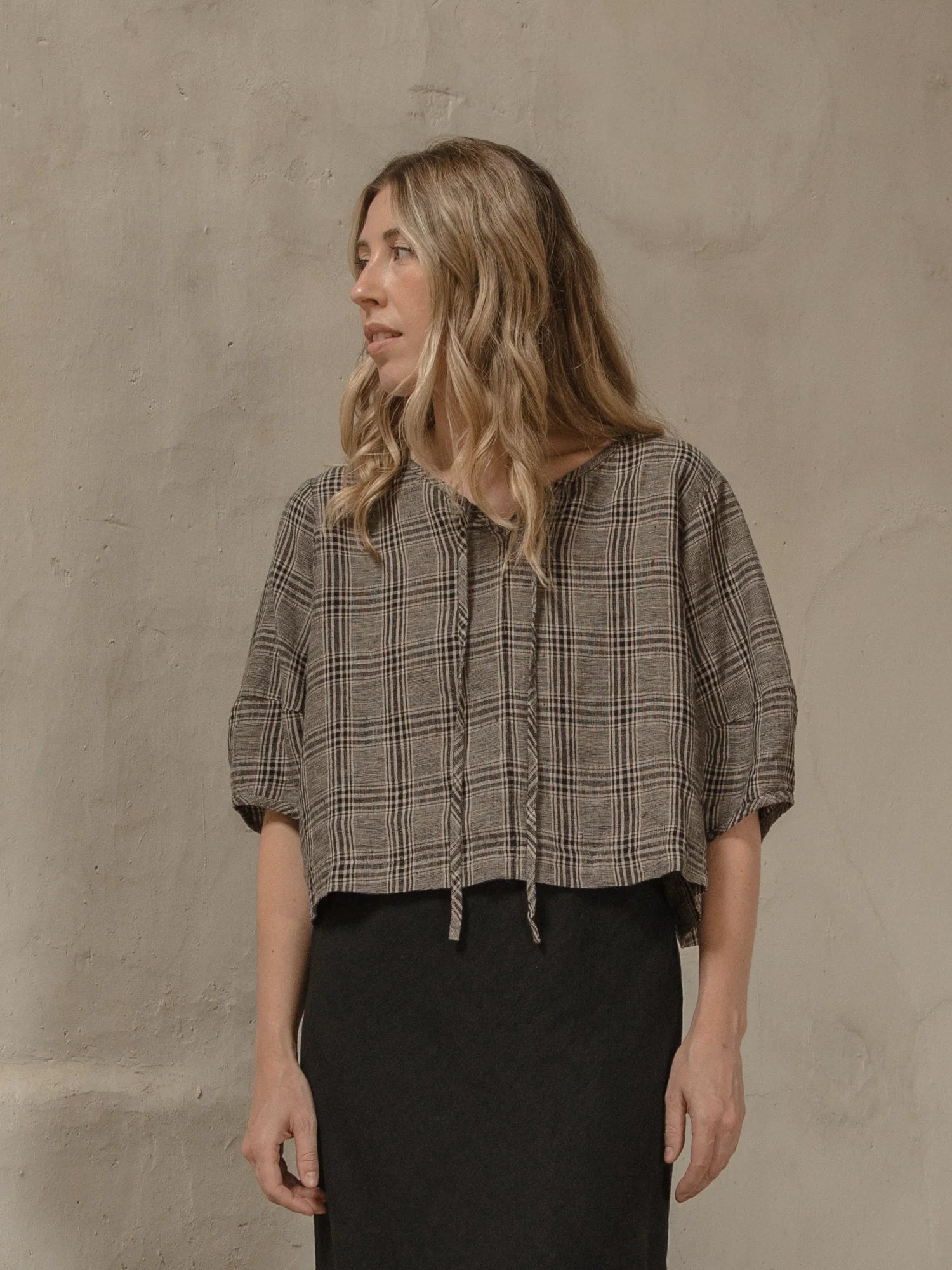 Woman wearing a plaid shirt against a beige wall