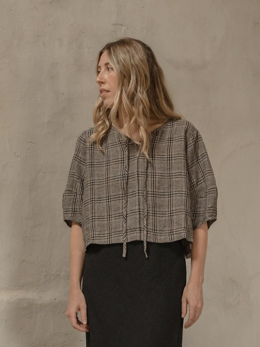 Woman wearing a plaid shirt against a beige wall