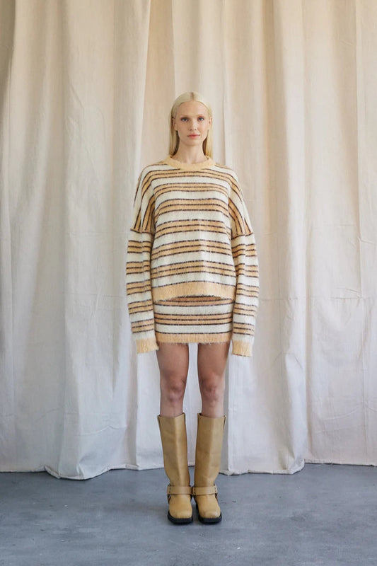 This image features a stylish knit mini skirt modeled by a woman, providing a clear view of how the garment fits and looks when worn. The skirt is characterized by a comfortable, slip-on design with a ribbed knit waistband that ensures a snug fit.