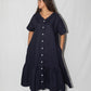 Woman wearing a navy blue dress with white buttons on a white background