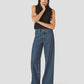 Woman wearing a black sleeveless top and blue jeans on a white background