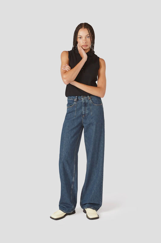 Woman wearing a black sleeveless top and blue jeans on a white background