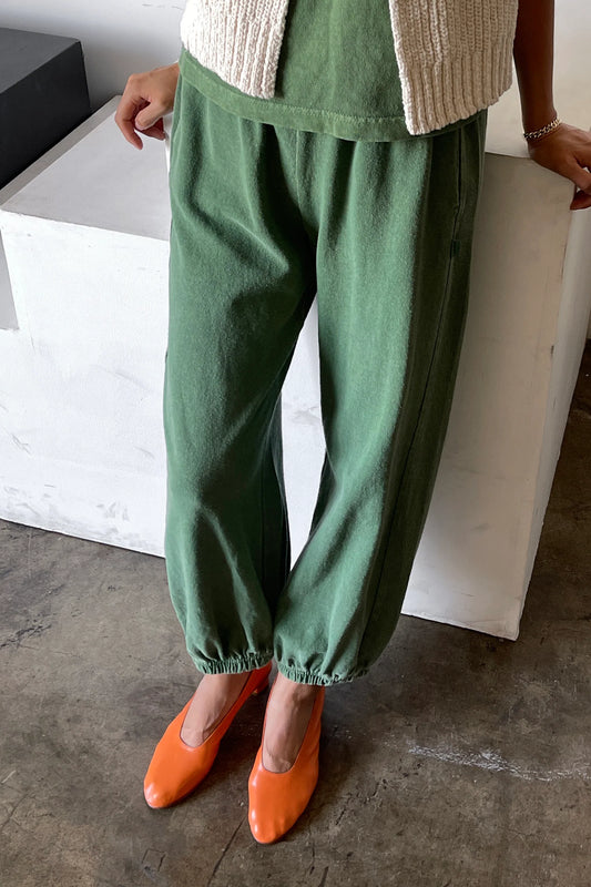 Person wearing green pants and orange shoes in a minimal indoor setting