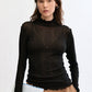 Woman wearing a black long-sleeve top with sheer sleeves on a white background
