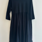 Navy blue dress on a hanger against a white background