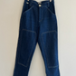 Blue jeans hanging on a wooden hanger against a white wall