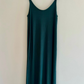 Green slip dress on a hanger against a white background
