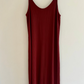 Maroon slip dress on a wooden hanger against a white background