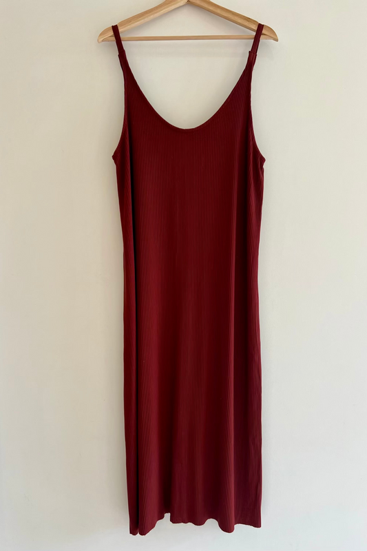 Maroon slip dress on a wooden hanger against a white background
