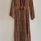 Brown patterned dress on a hanger against a white wall