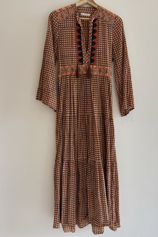 Brown patterned dress on a hanger against a white wall