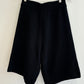 Black shorts on a wooden hanger against a white background