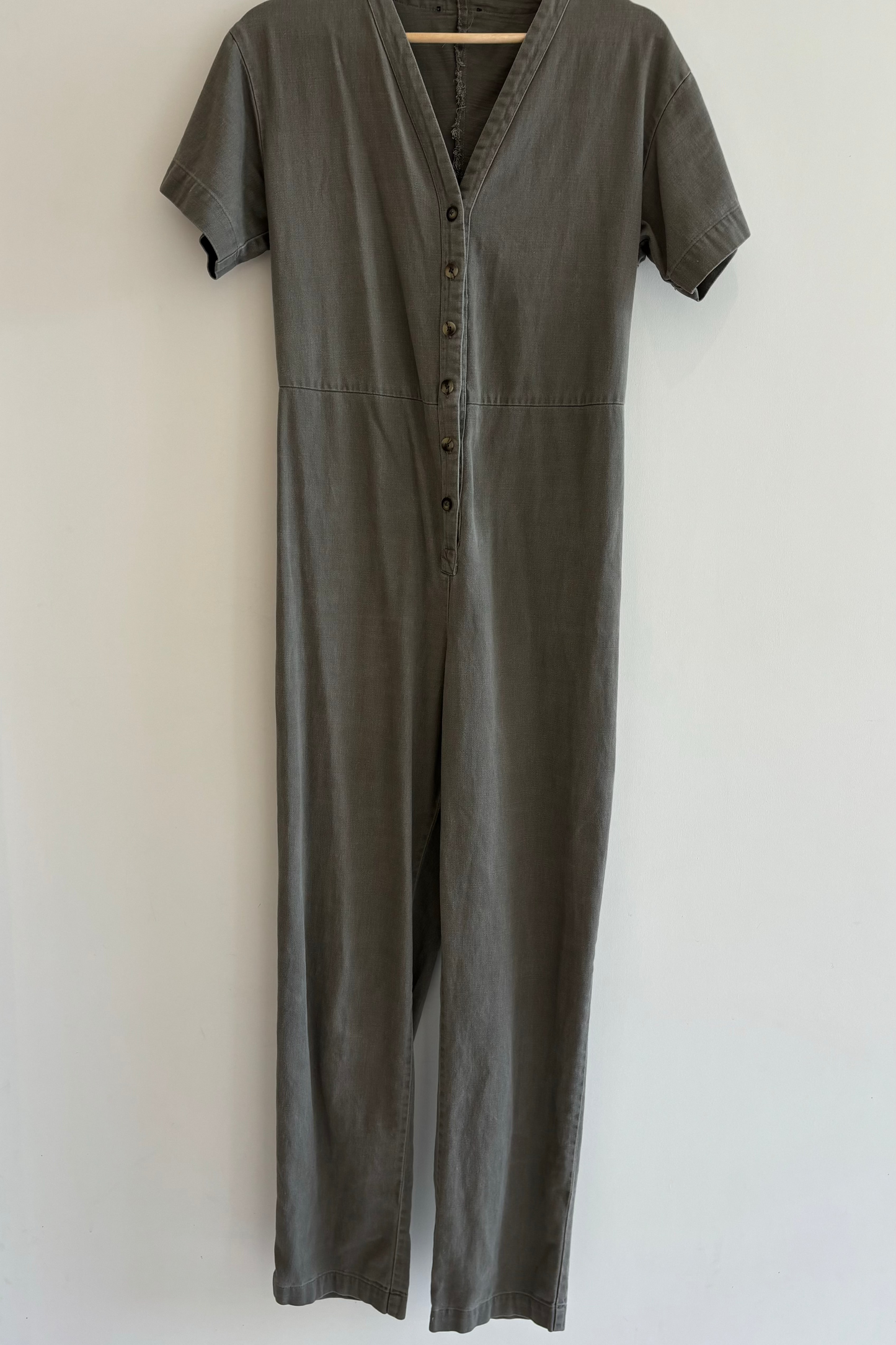 Gray jumpsuit on a hanger against a white background