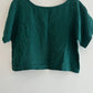 Green blouse on a wooden hanger against a white background