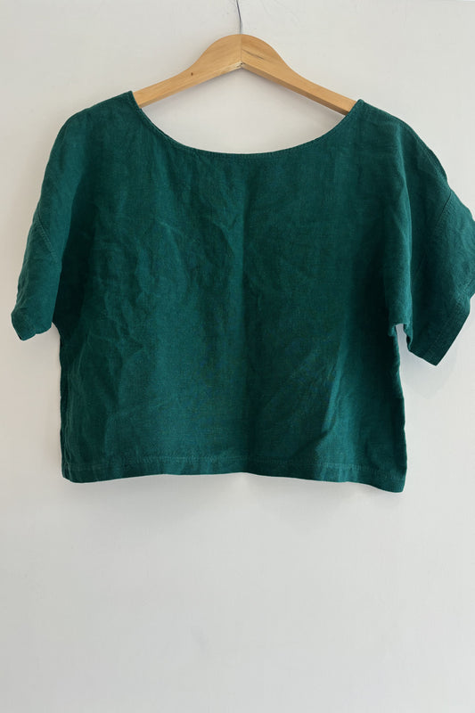 Green blouse on a wooden hanger against a white background