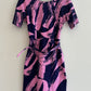 Pink and navy abstract patterned dress on a hanger against a white background
