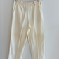 Beige pants hanging on a wooden hanger against a white wall