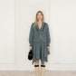 Woman wearing a checkered dress with beige boots in a minimal indoor setting
