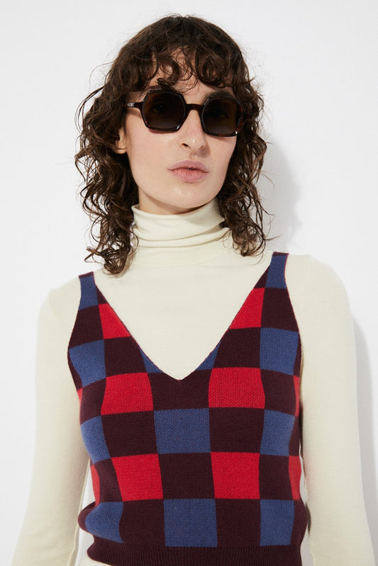 A person wearing a checkered red and blue cotton knit top with thin straps and a v-neck.