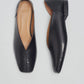 Pair of black leather  slipper shoes with a central seam, tulip shaped upper, squared-off toe and 3/4" heel on a light gray background
