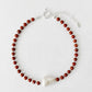 Necklace with red beads and a white pearl on a white background