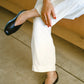 Person wearing white pants and black leather slipper shoe with central seam and tulip shaped upper with squared-off toe and 3/4" heel. 