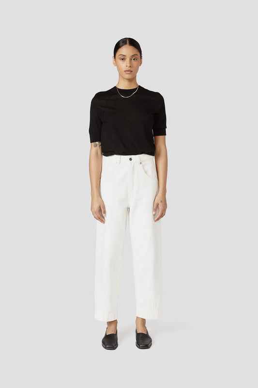 Person wearing a black top and white pants on a white background
