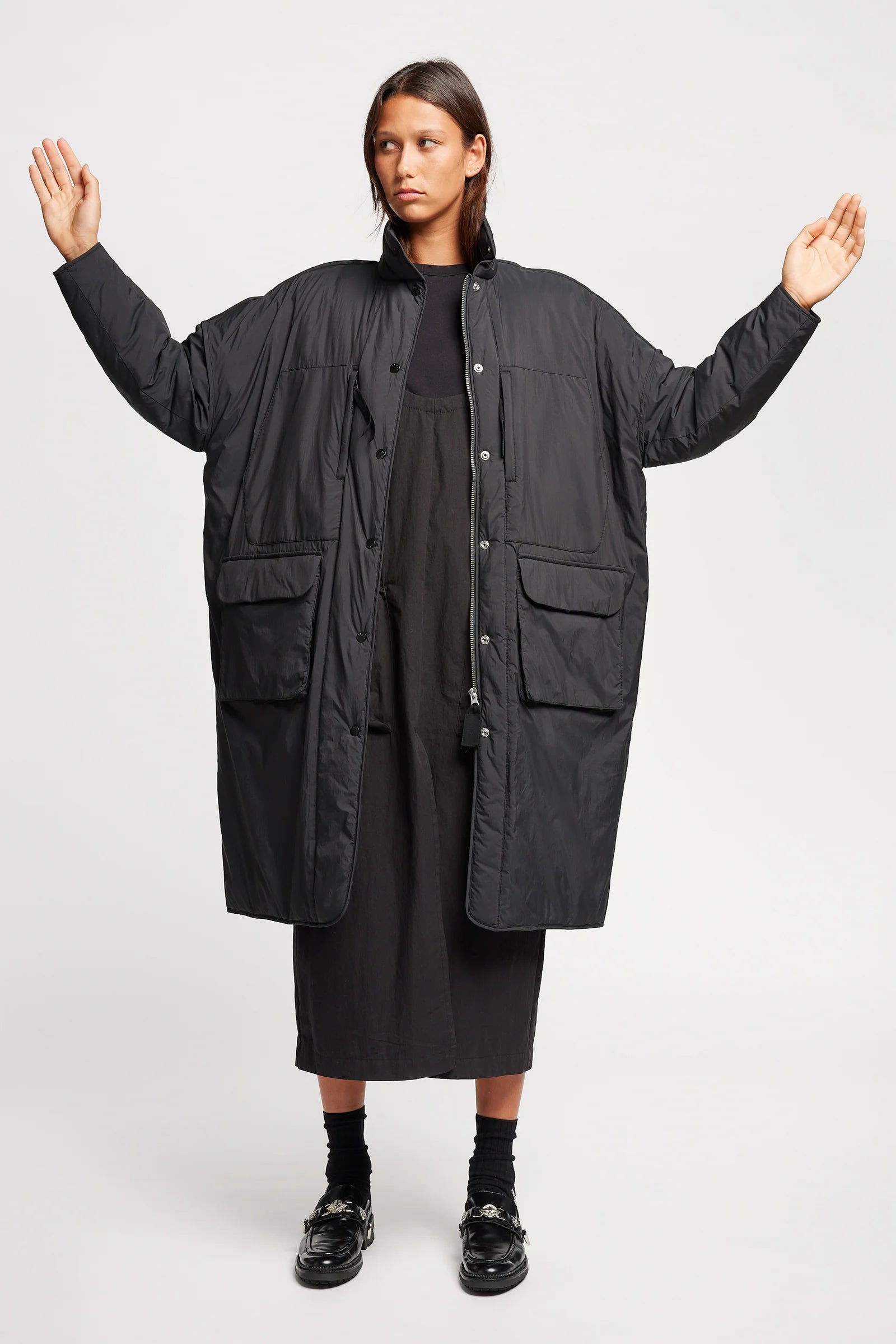 Person wearing a long black coat on a white background