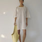 Bohème Goods Fisherman Tee in cream open net cotton worn as a beach coverup with jelly sandals and a lime green tote bag against a white studio background